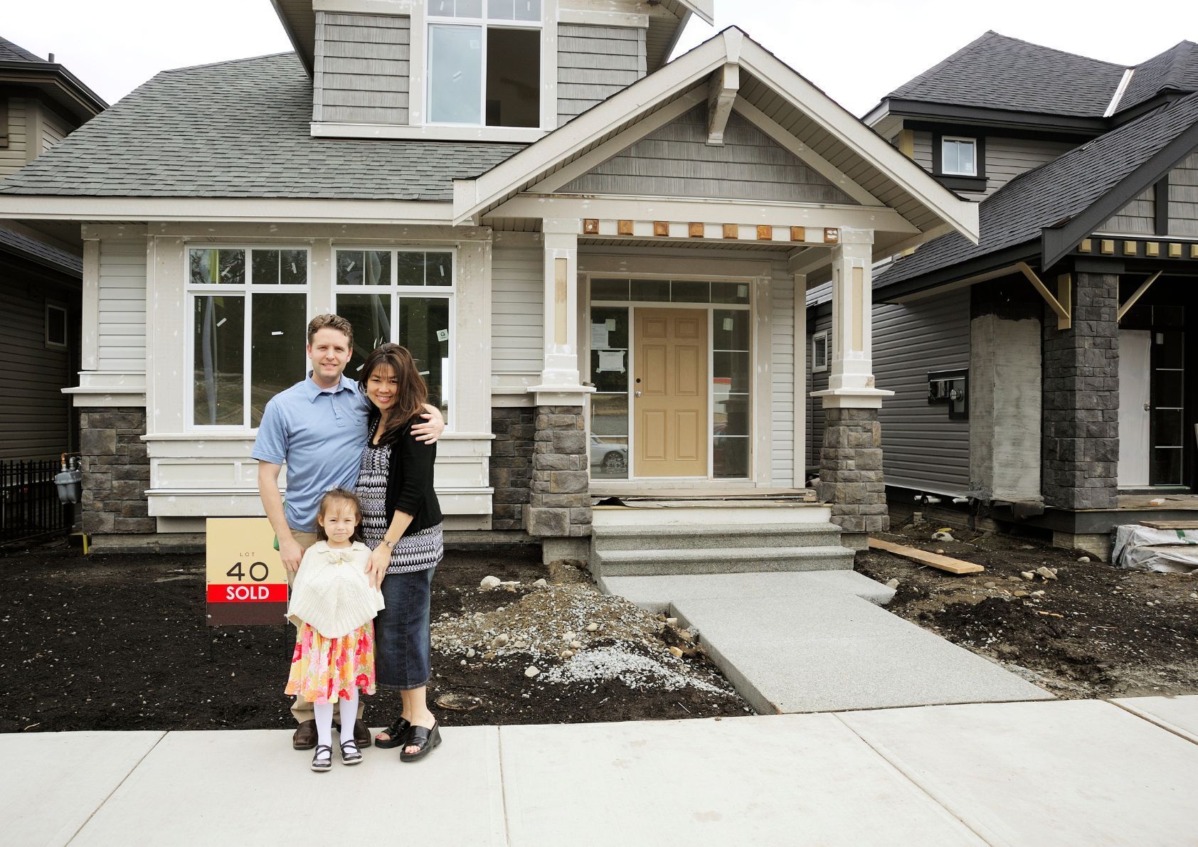 A Couple with their daughter in front of their new home,.