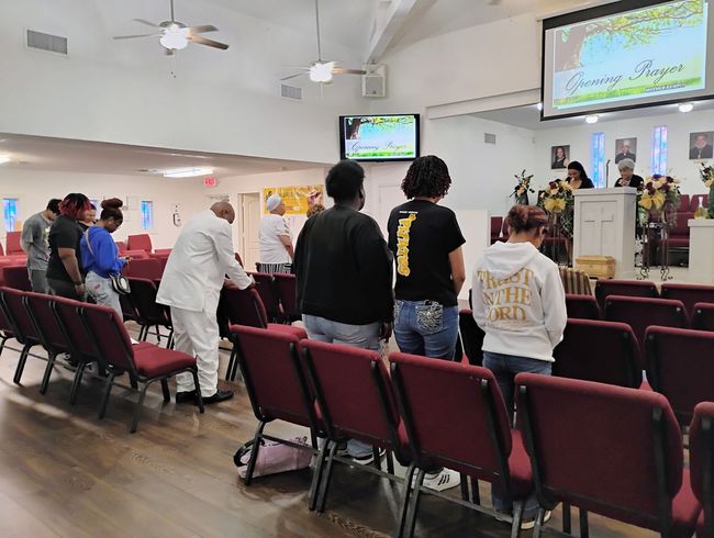 A group of people are sitting in rows of red chairs in a church.