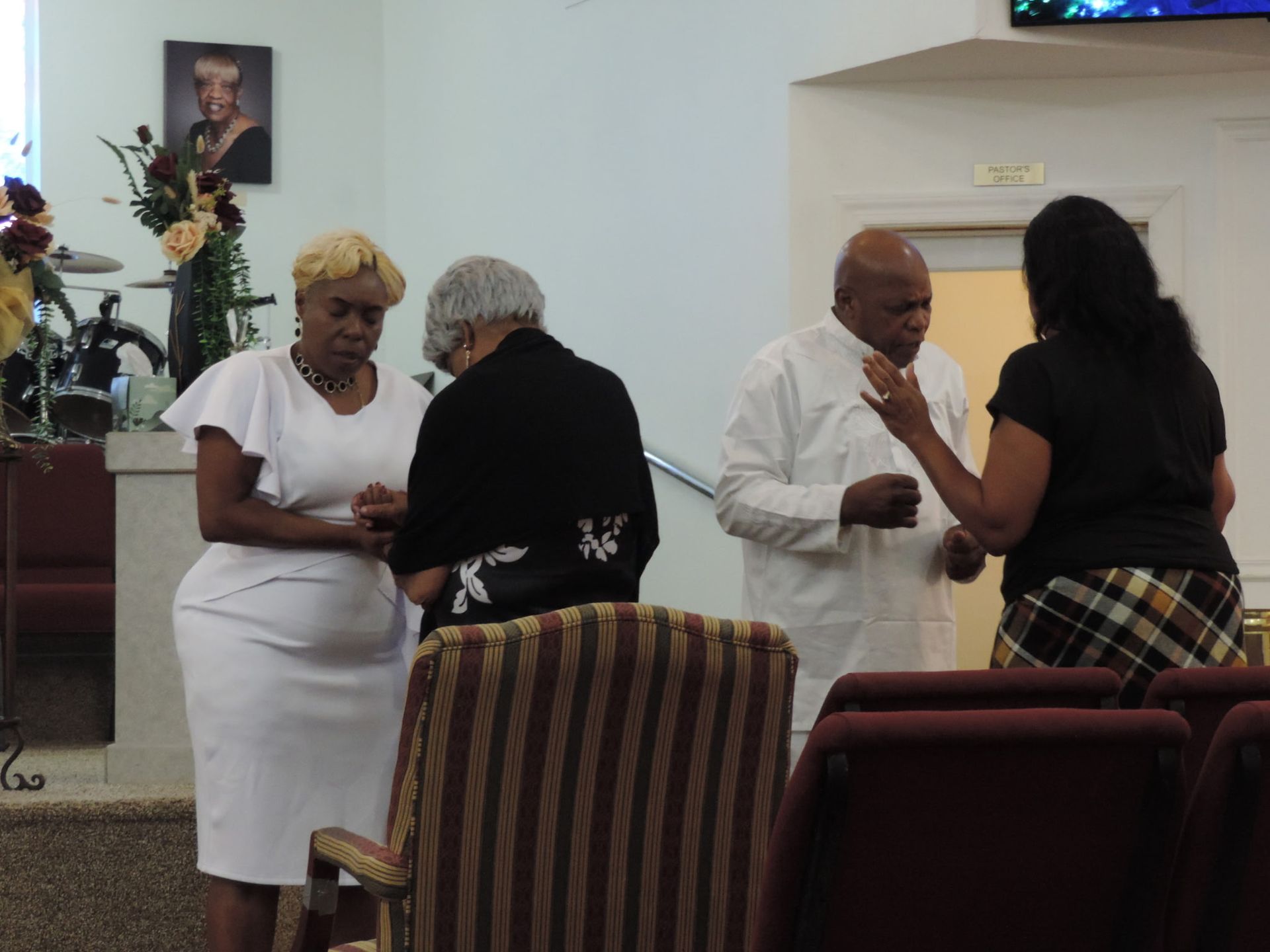 A group of people are standing in a room talking to each other