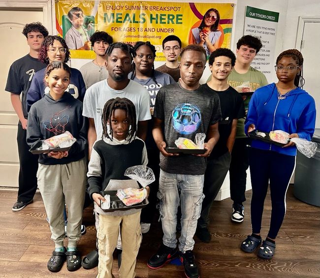 A group of people standing next to each other holding plates of food.