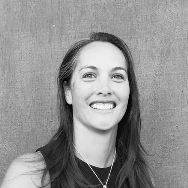 A woman is smiling in a black and white photo while wearing a necklace.
