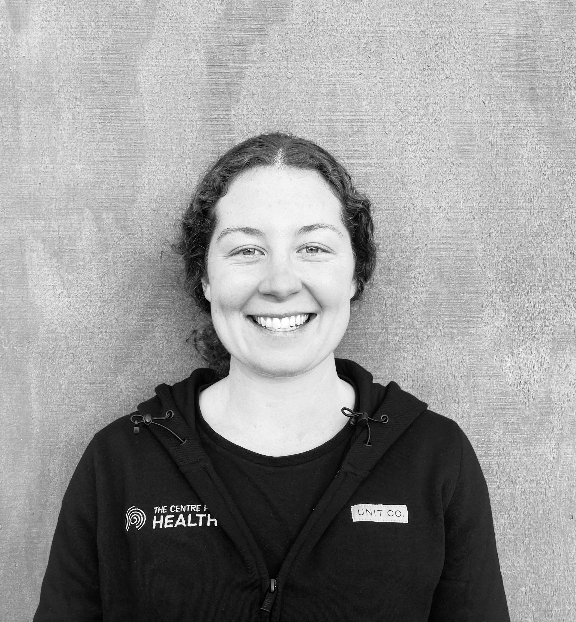 A black and white photo of a woman wearing a necklace and smiling.