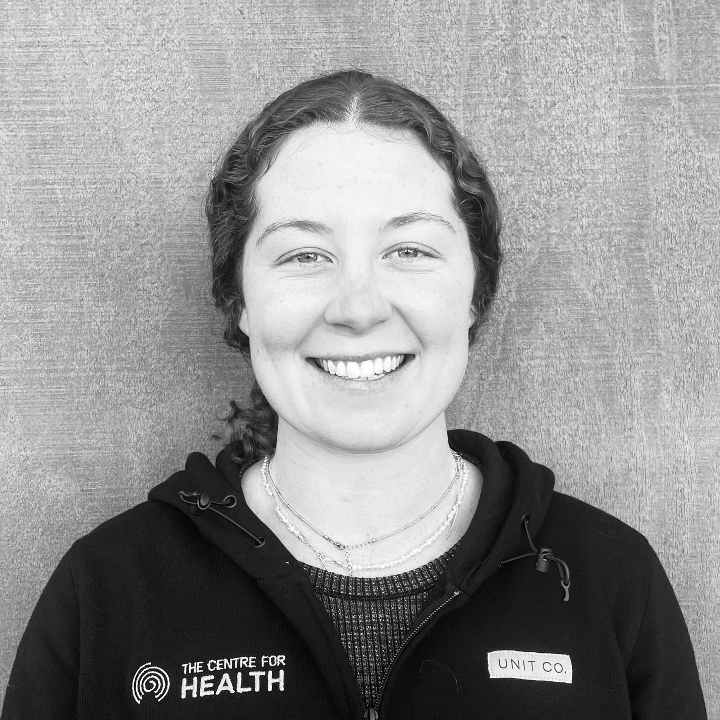 A black and white photo of a woman wearing a hoodie and smiling.