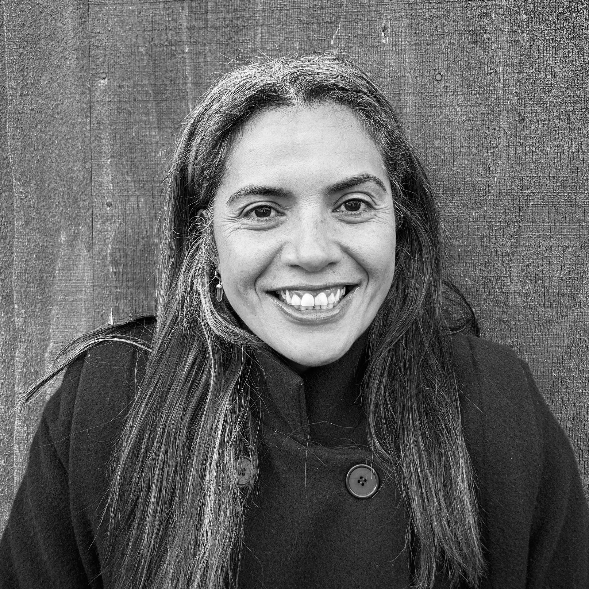 A woman with long hair is smiling in a black and white photo.