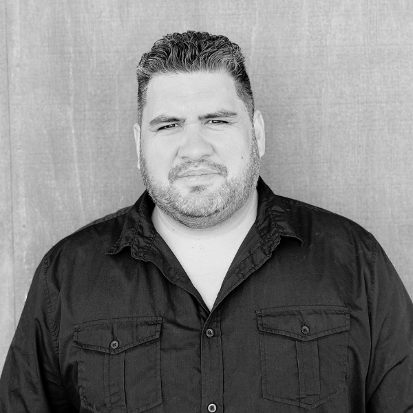 A black and white photo of a man with a beard wearing a black shirt.