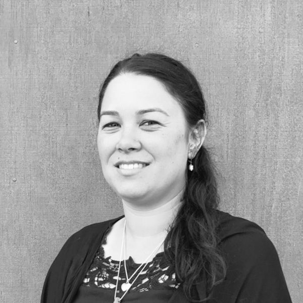 A woman is smiling in a black and white photo while standing in front of a wall.