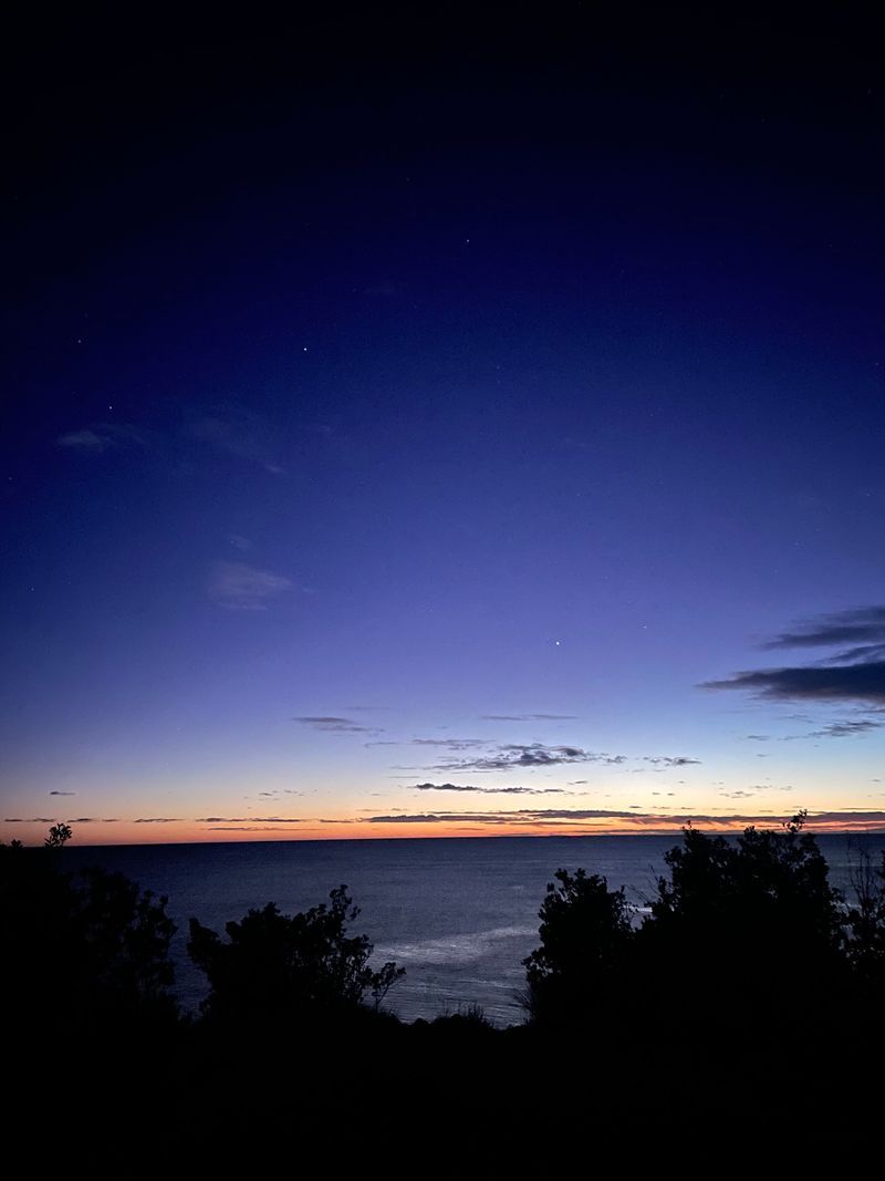 A group of people are sitting on a wall next to a beach.