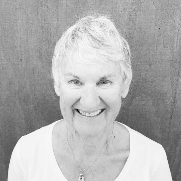 An older woman is smiling in a black and white photo.
