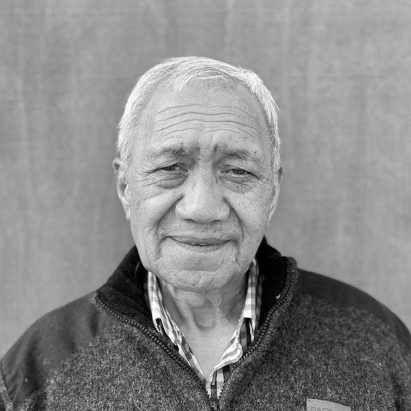A black and white photo of an older man wearing a sweater.