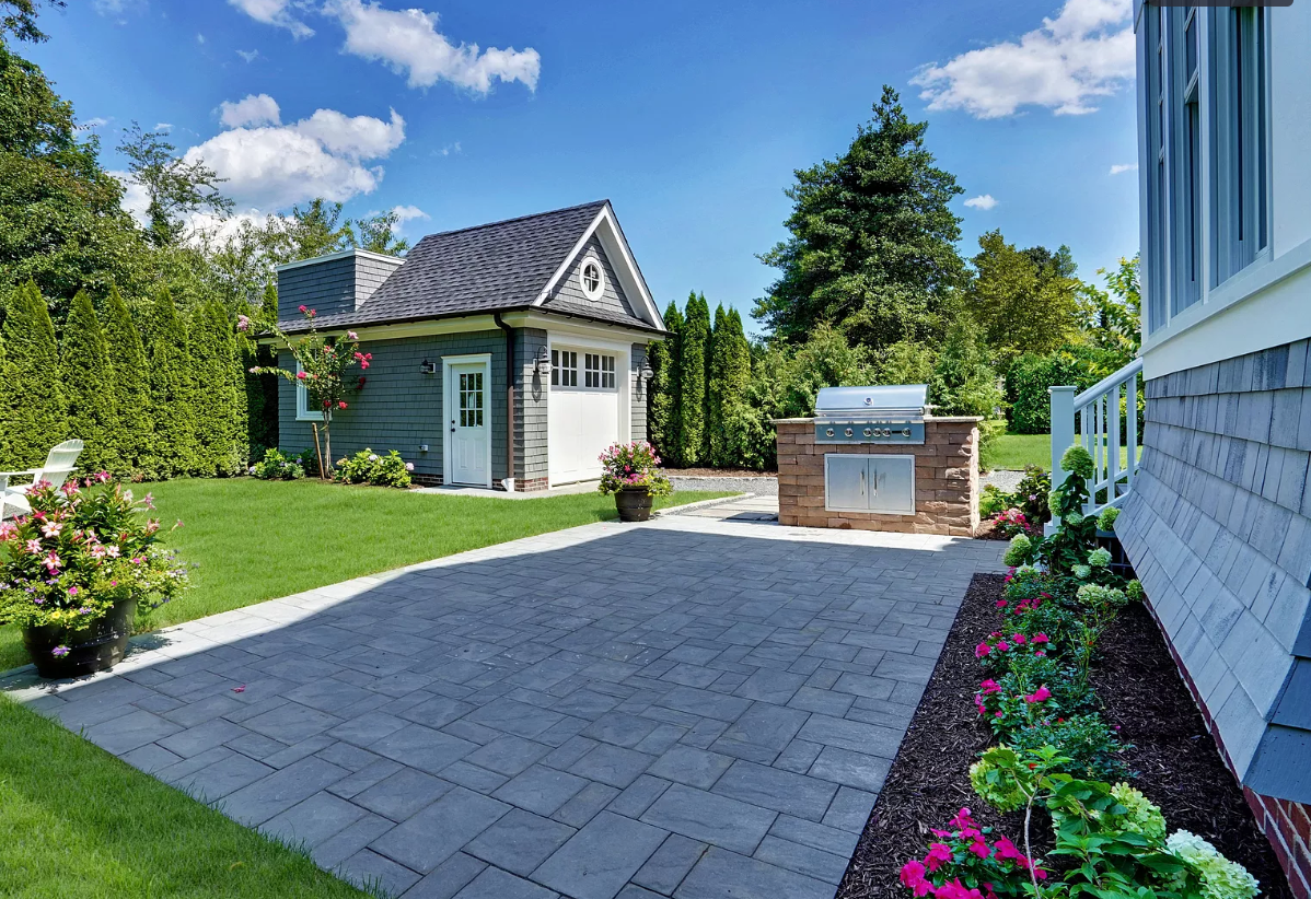 A house with a garage and a grill in front of it.