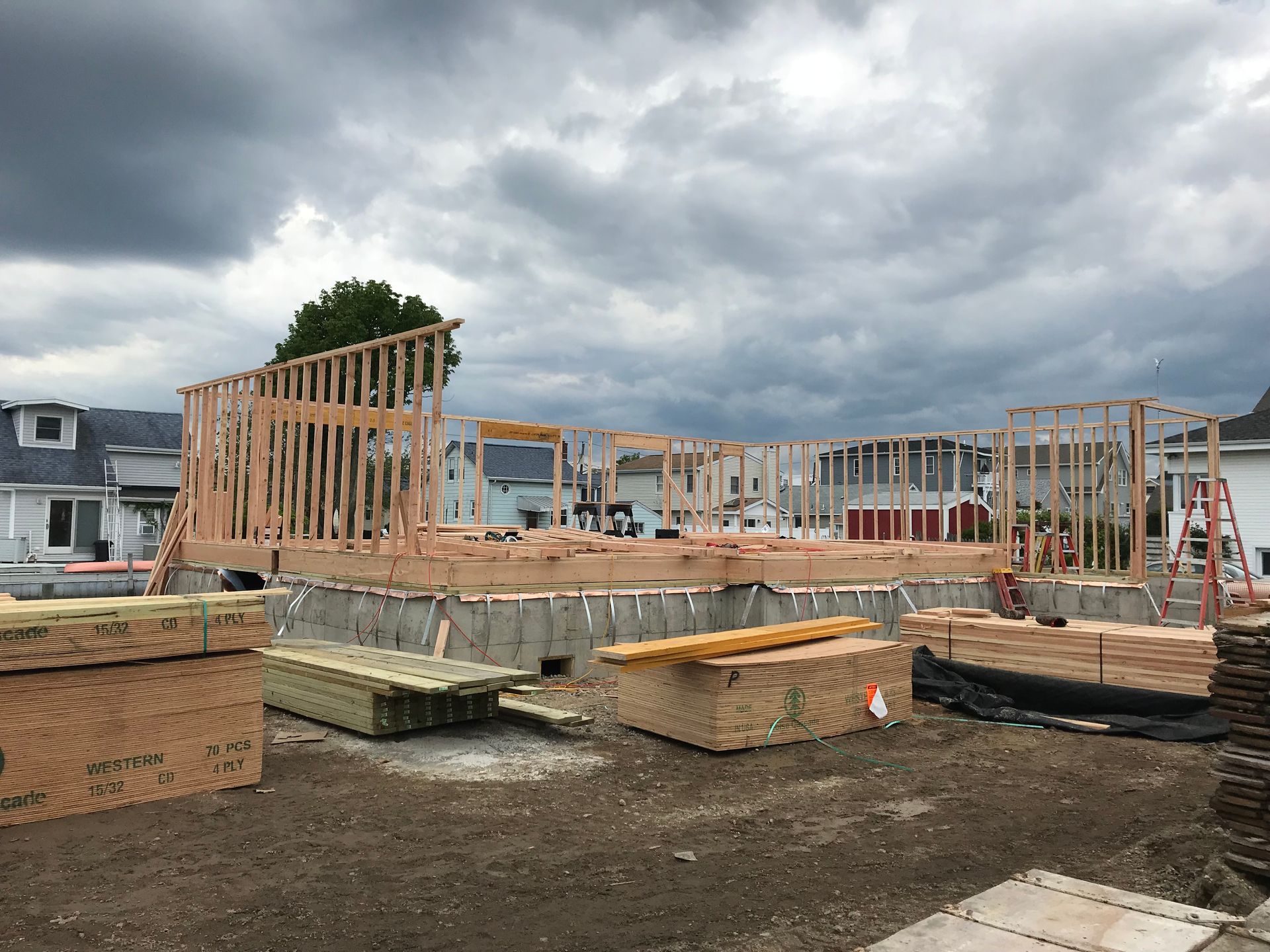 A house is being built in a lot with a cloudy sky in the background.