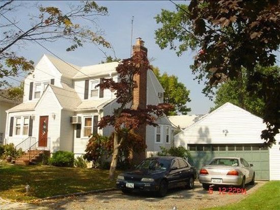 A white house with a black car parked in front of it