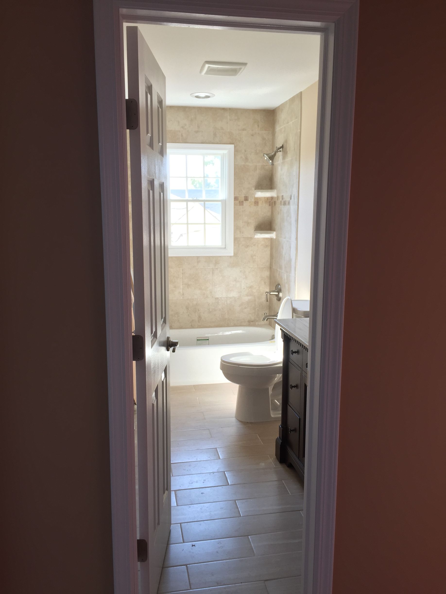 A bathroom with a toilet , sink , tub and window.