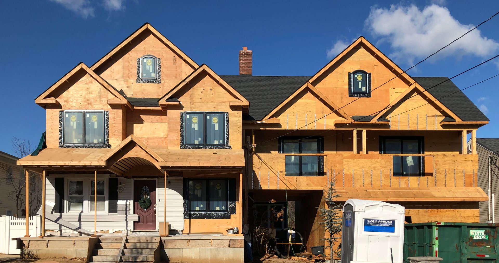 Two houses are being built next to each other on a sunny day.