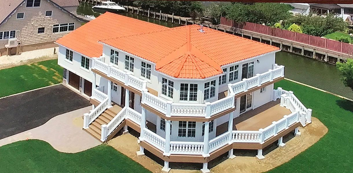 An aerial view of a large white house with a red roof