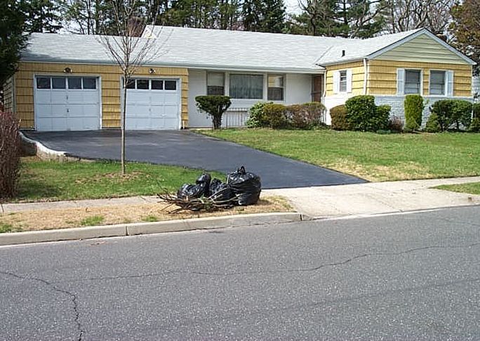 A yellow and white house with a black driveway