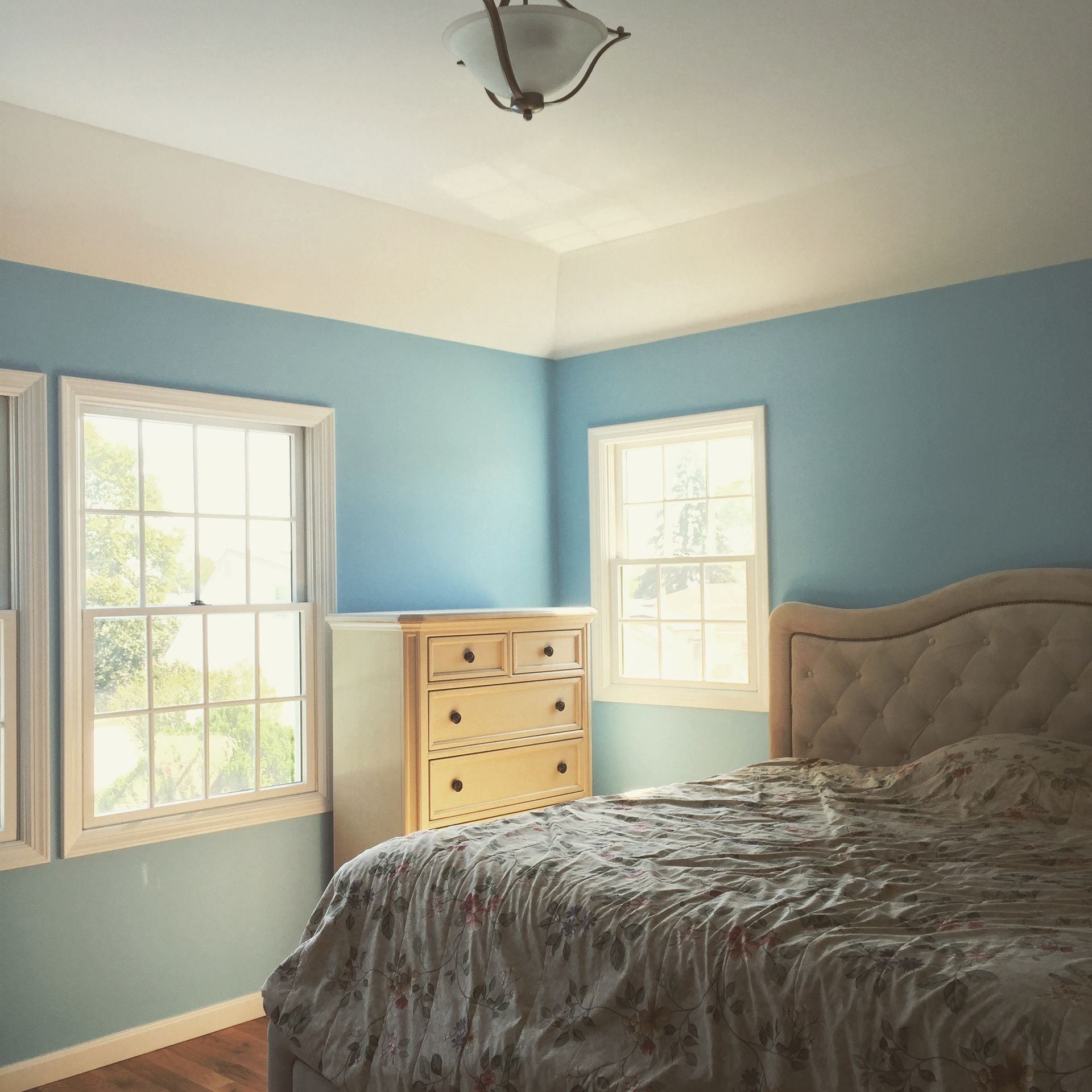 A bedroom with blue walls and a bed and dresser