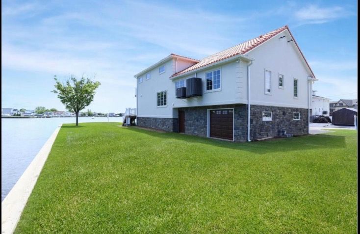 A large white house sits on a small island in the middle of a body of water.