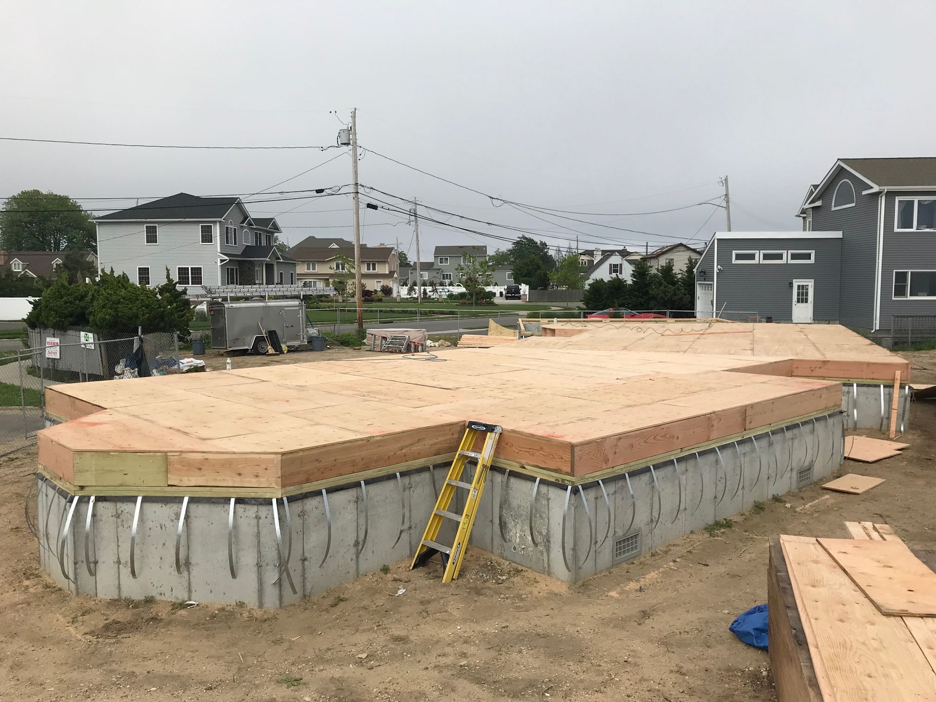 A ladder is sitting on the ground in front of a house under construction.