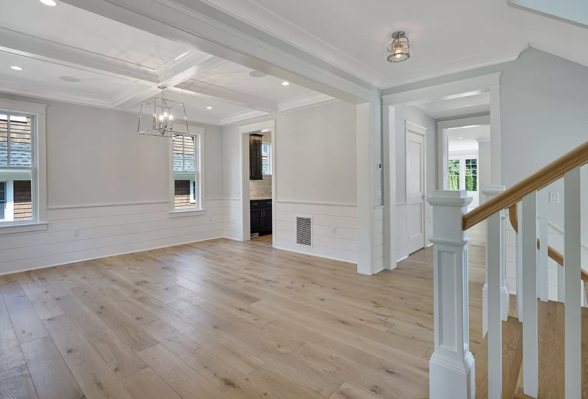 An empty living room with hardwood floors and stairs in a house.
