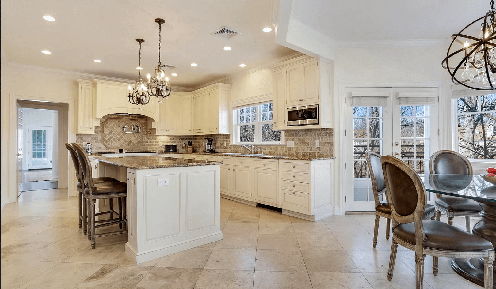 A kitchen with white cabinets and granite counter tops and a dining room with a table and chairs.