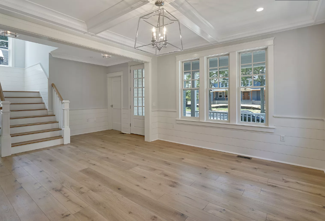 An empty living room with hardwood floors and stairs.