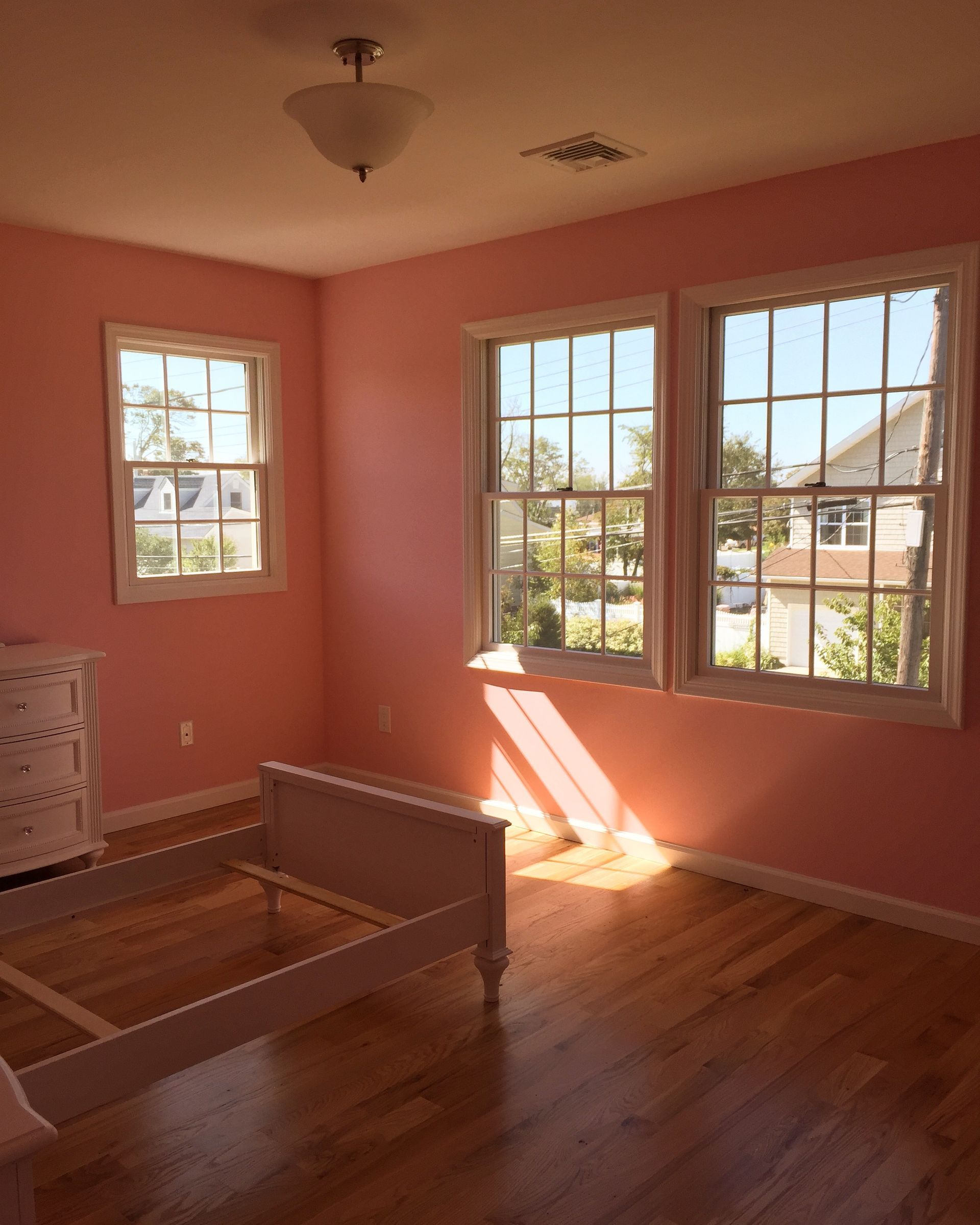 A bedroom with pink walls and a white bed