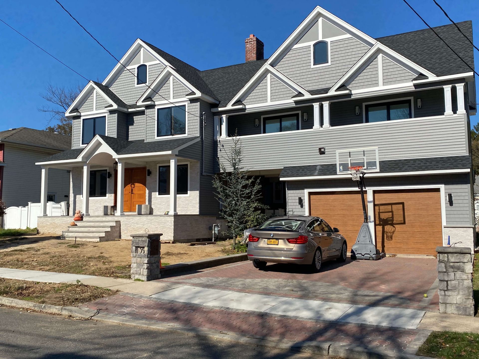A car is parked in front of a house with a basketball hoop
