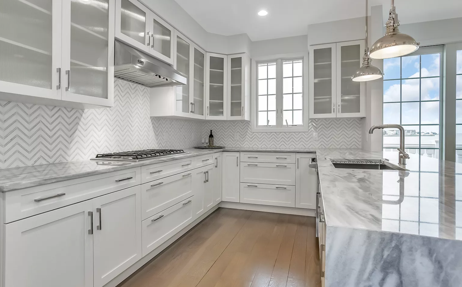 A kitchen with white cabinets and marble counter tops