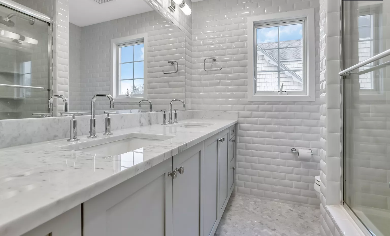 A bathroom with two sinks , a shower and a window.
