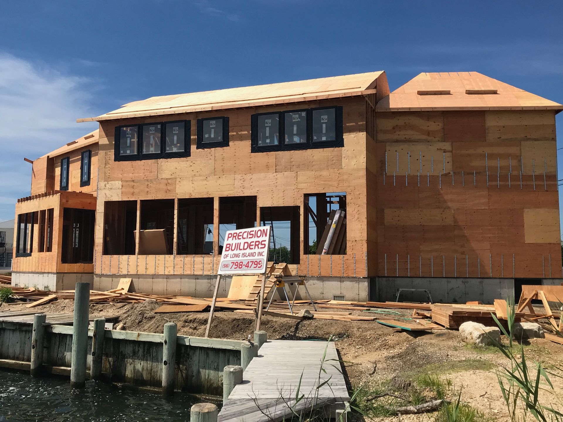 A large house is being built next to a body of water.