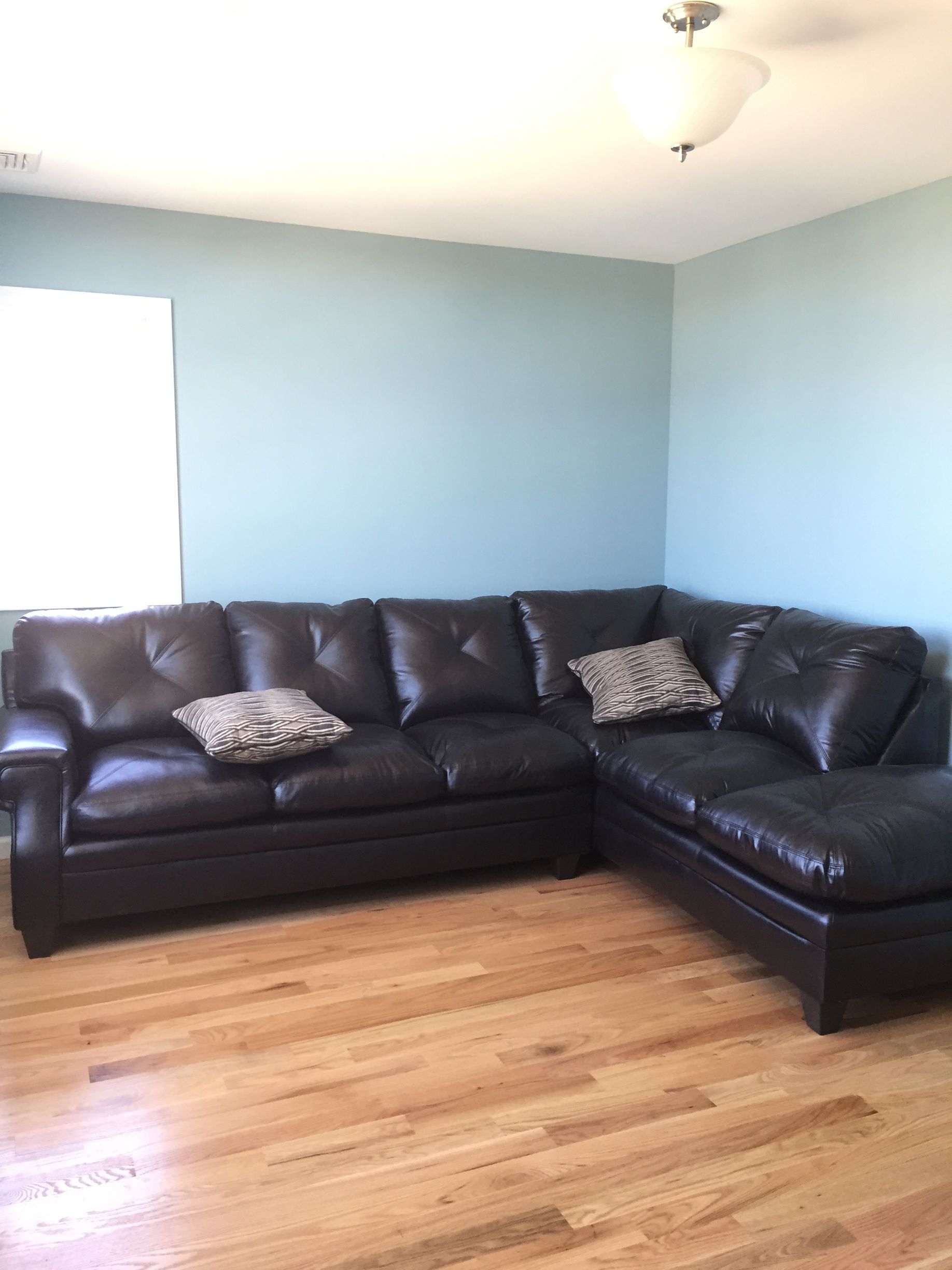 A living room with a large black leather sectional couch.