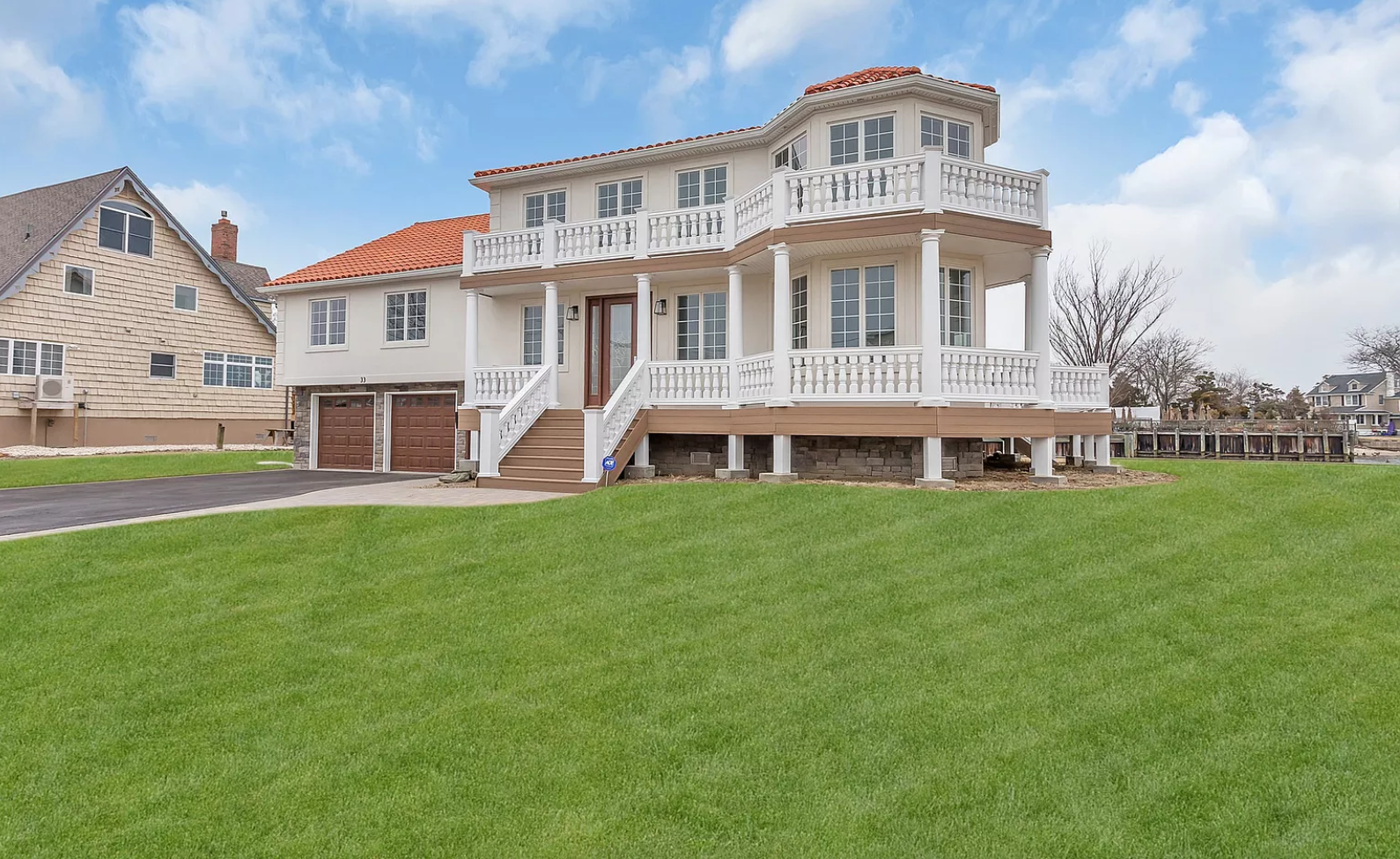 A large white house with a red roof is sitting on top of a lush green field.