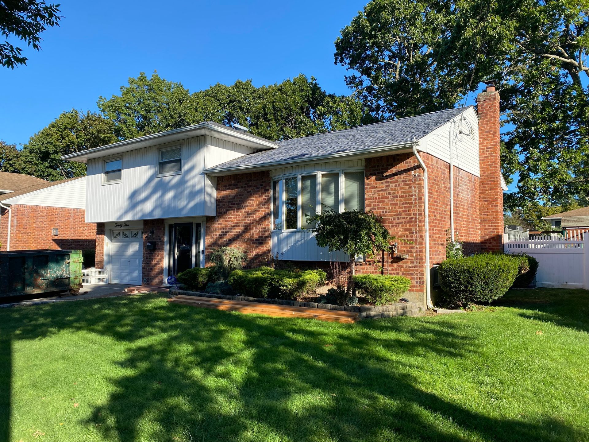 A brick house with a white trim and a large lawn in front of it.