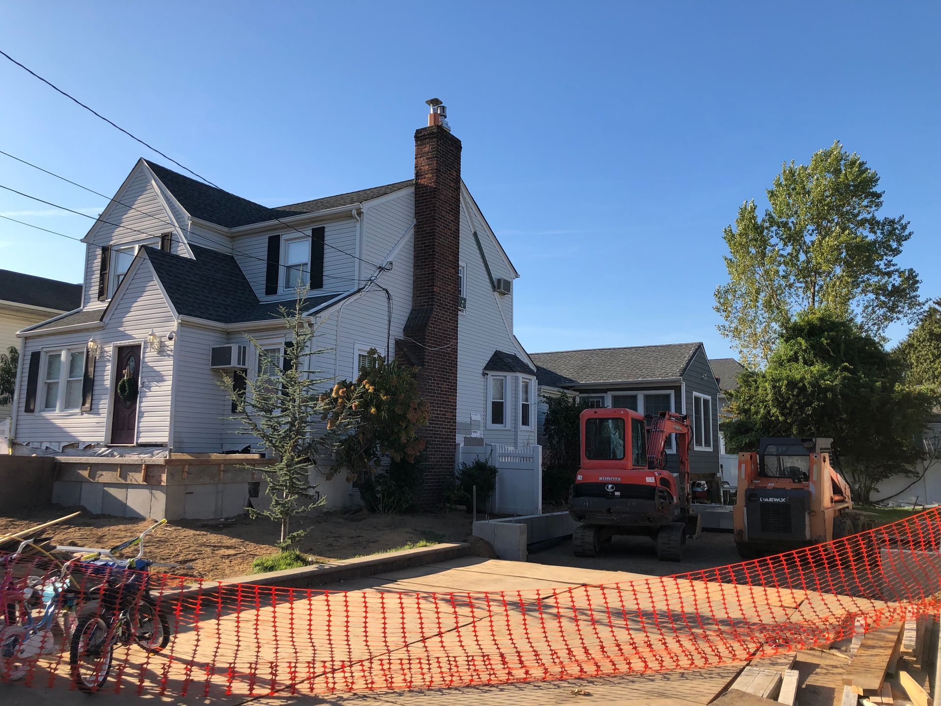 A large white house with a red excavator in front of it.