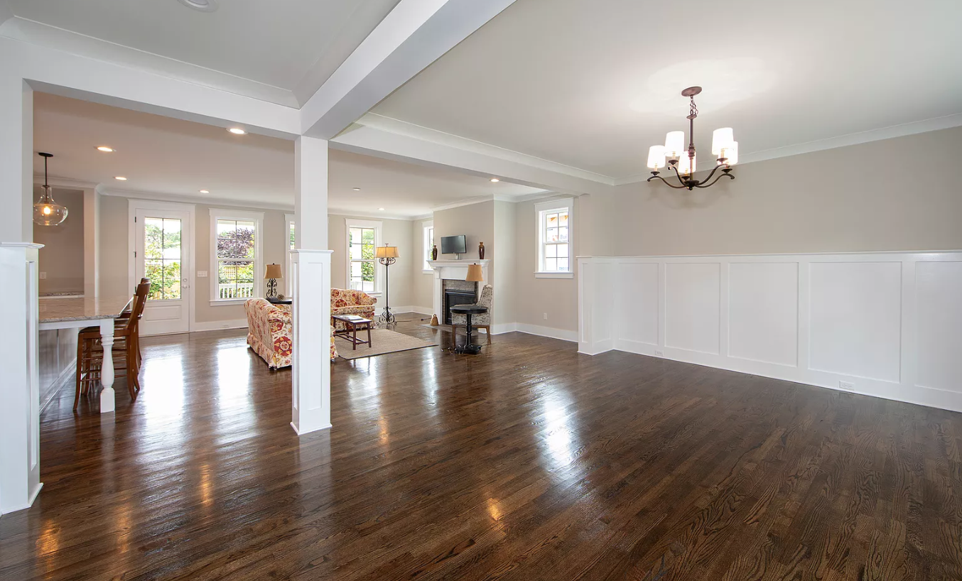 A large empty room with hardwood floors and a chandelier.