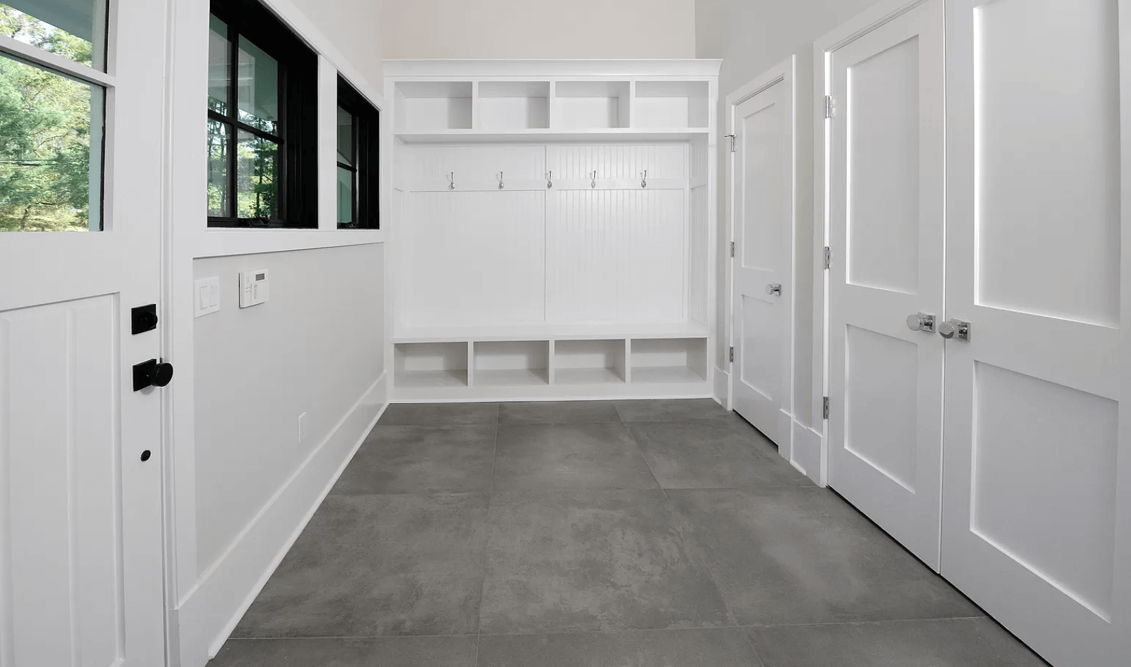 A hallway with white doors and a gray tile floor.