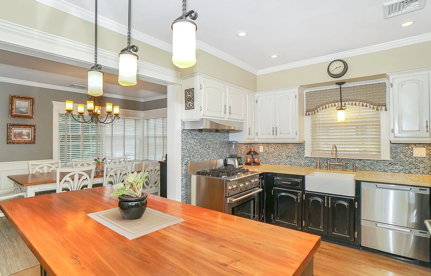 A kitchen with a large wooden table and stainless steel appliances.