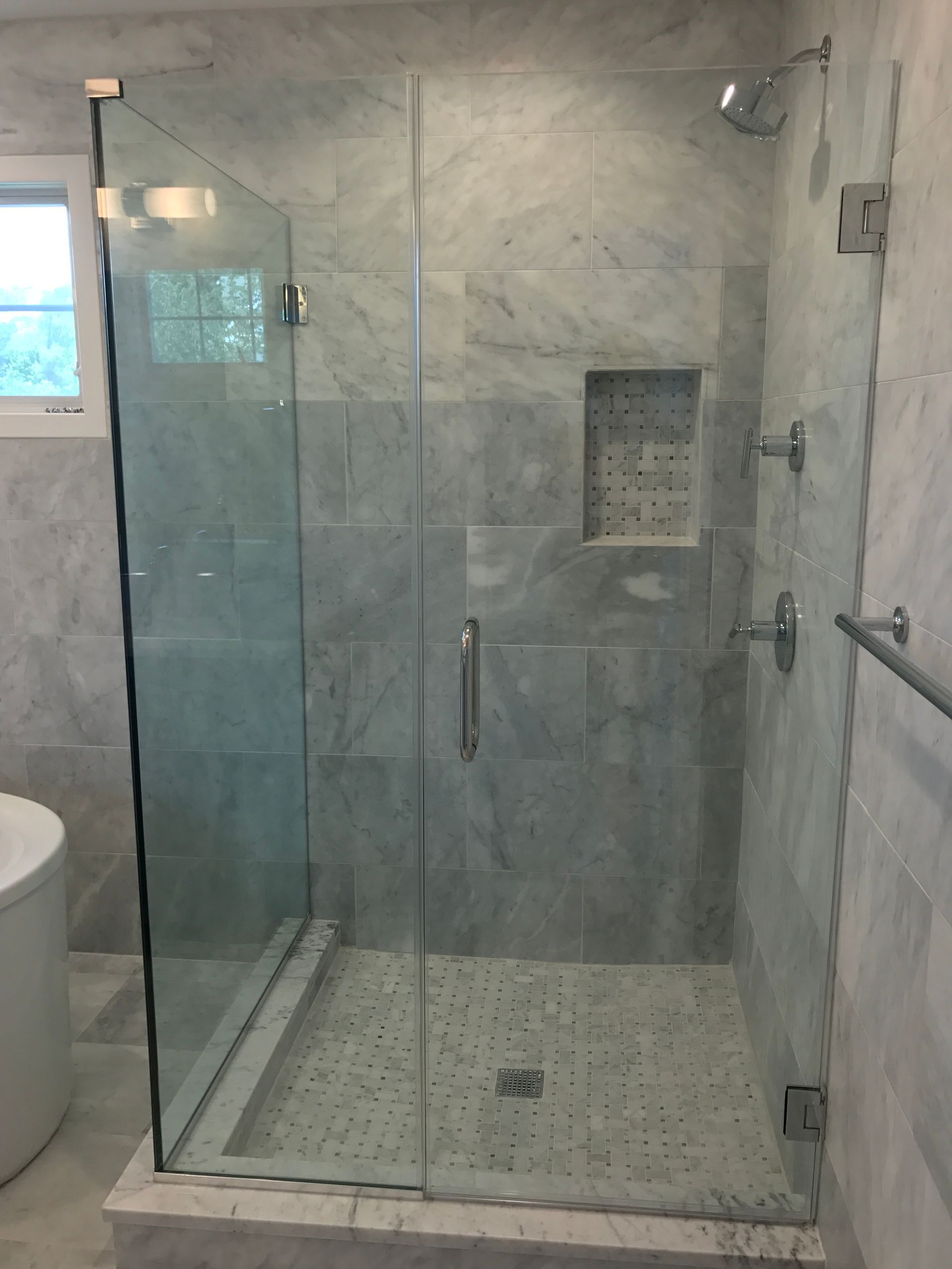 A bathroom with a walk in shower with a glass door
