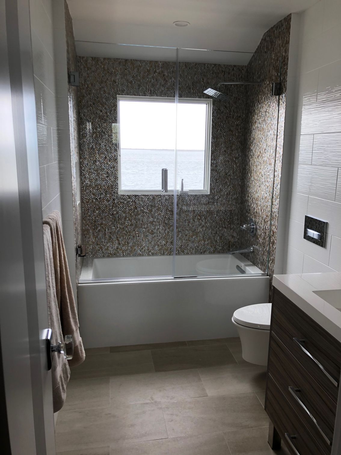 A bathroom with a tub , toilet , sink and window.