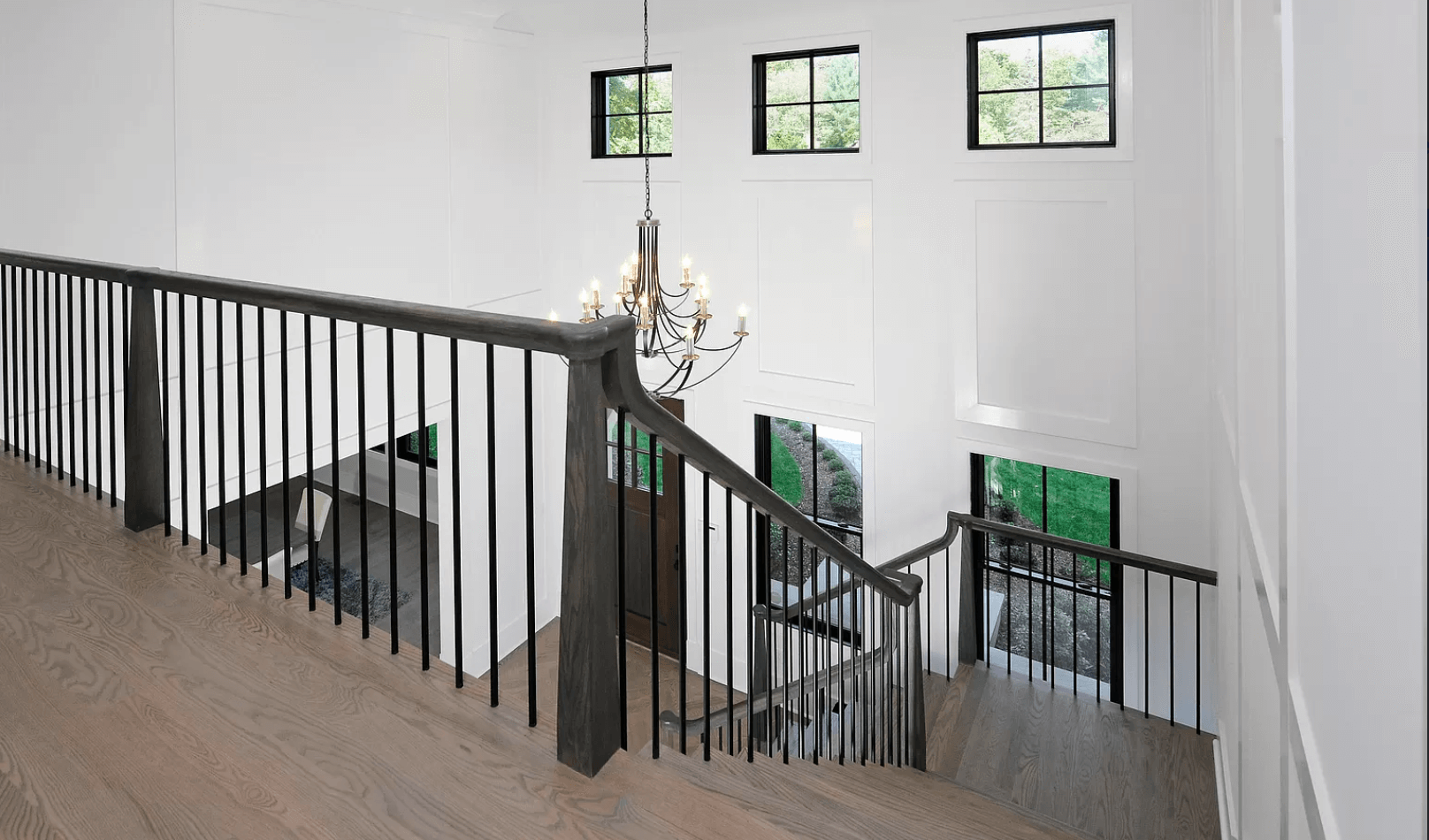 A staircase with a black railing and a chandelier hanging from the ceiling.
