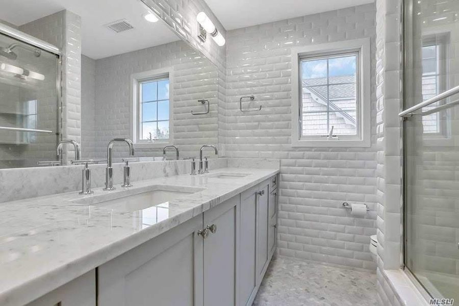 A bathroom with two sinks , a large mirror and a window.