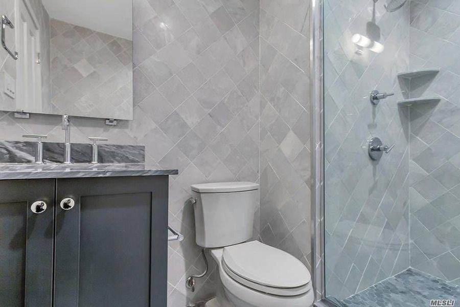 A bathroom with a toilet , sink and shower.