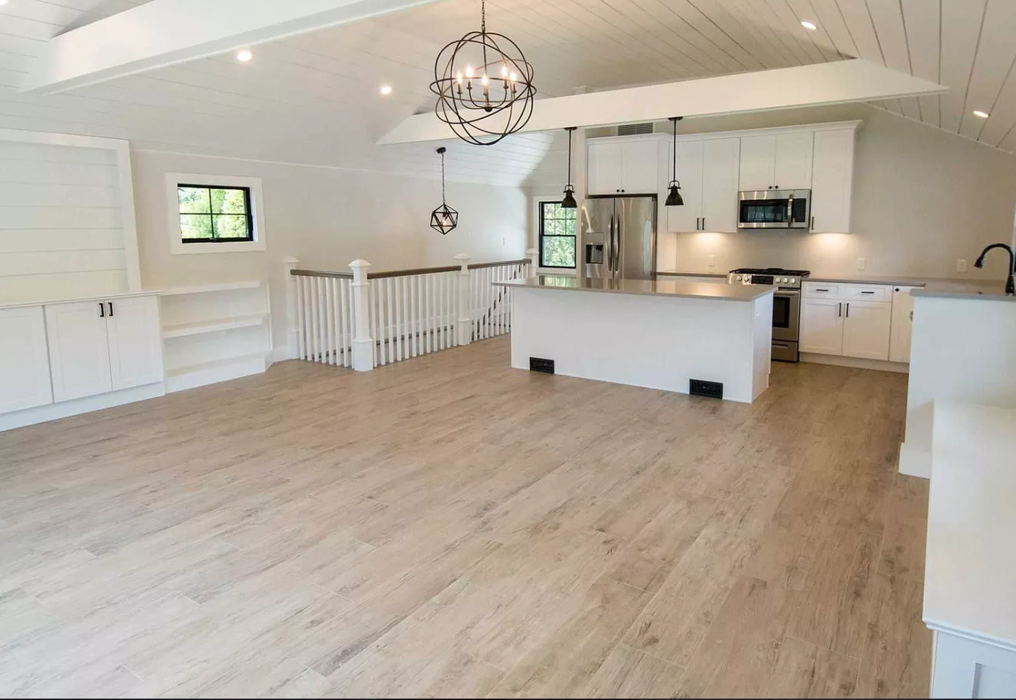 An empty kitchen with white cabinets and a large island