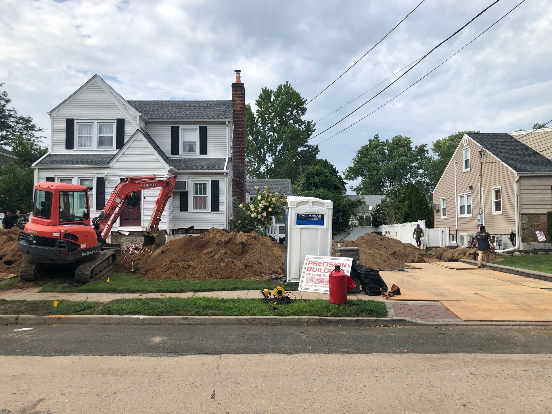 A red excavator is parked in front of a house.