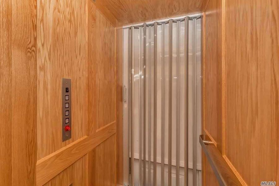 A wooden elevator with a white curtain on the door.