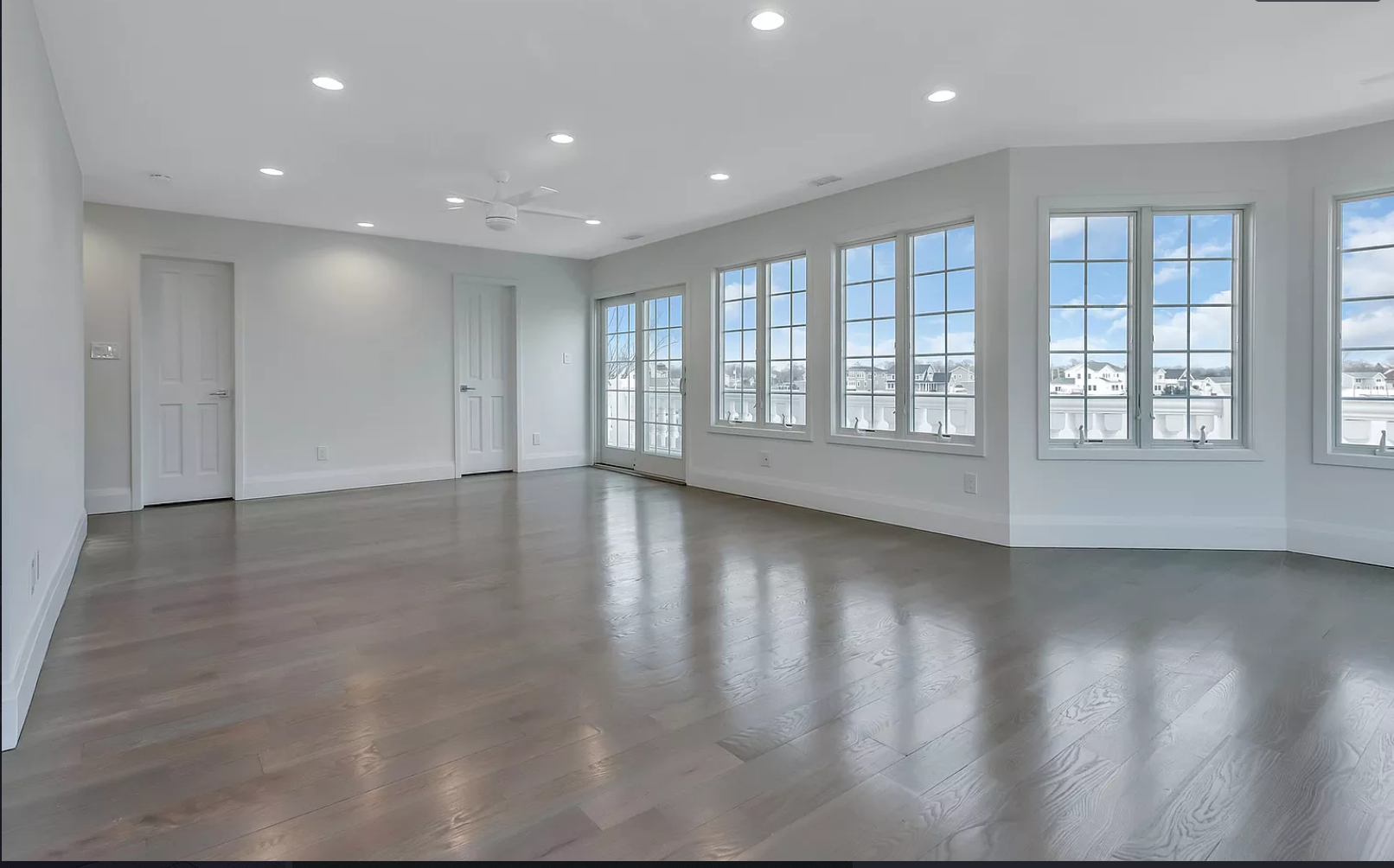 A large empty room with hardwood floors and lots of windows.