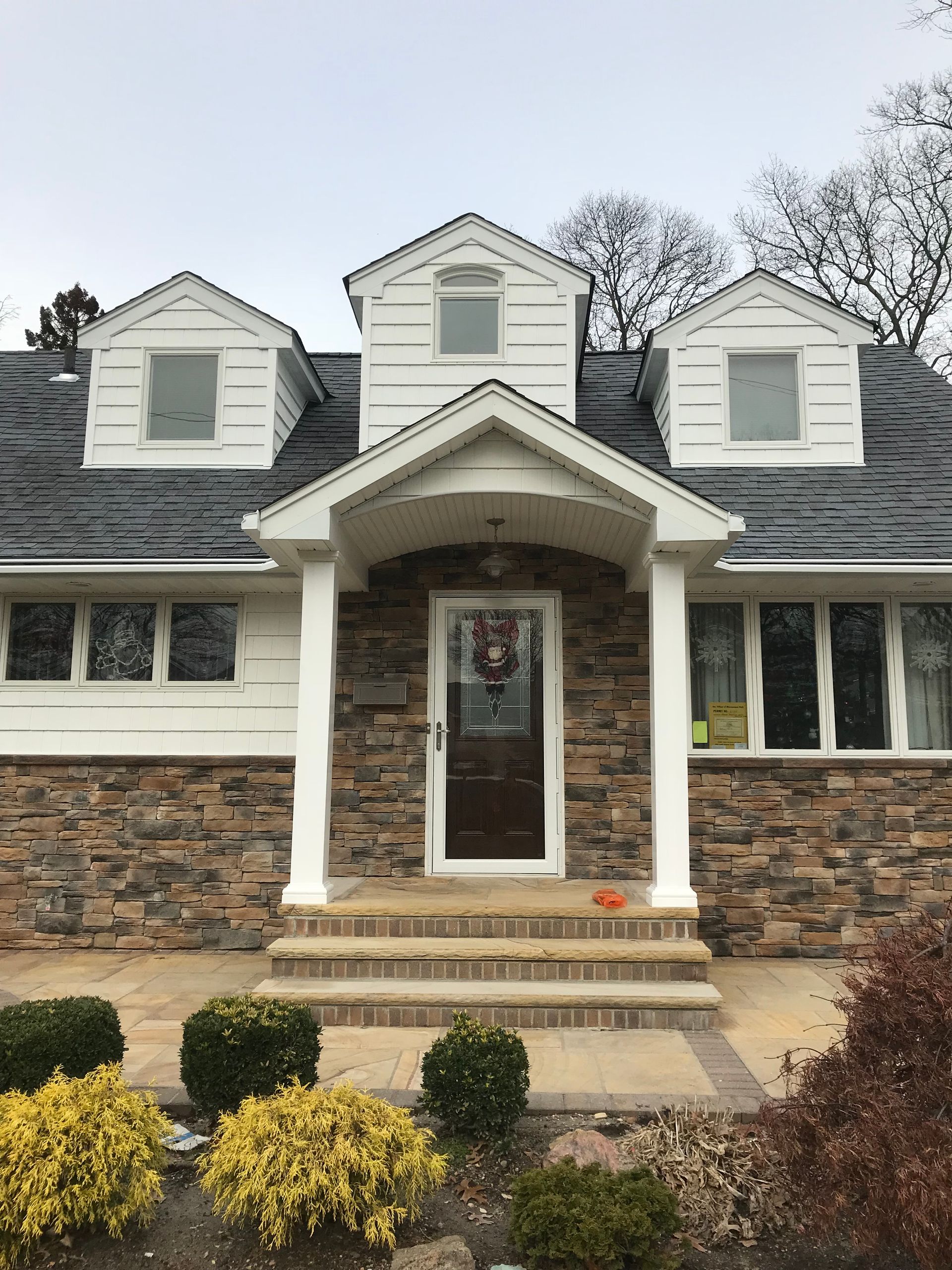 The front of a house with a stone facade and a white trim.