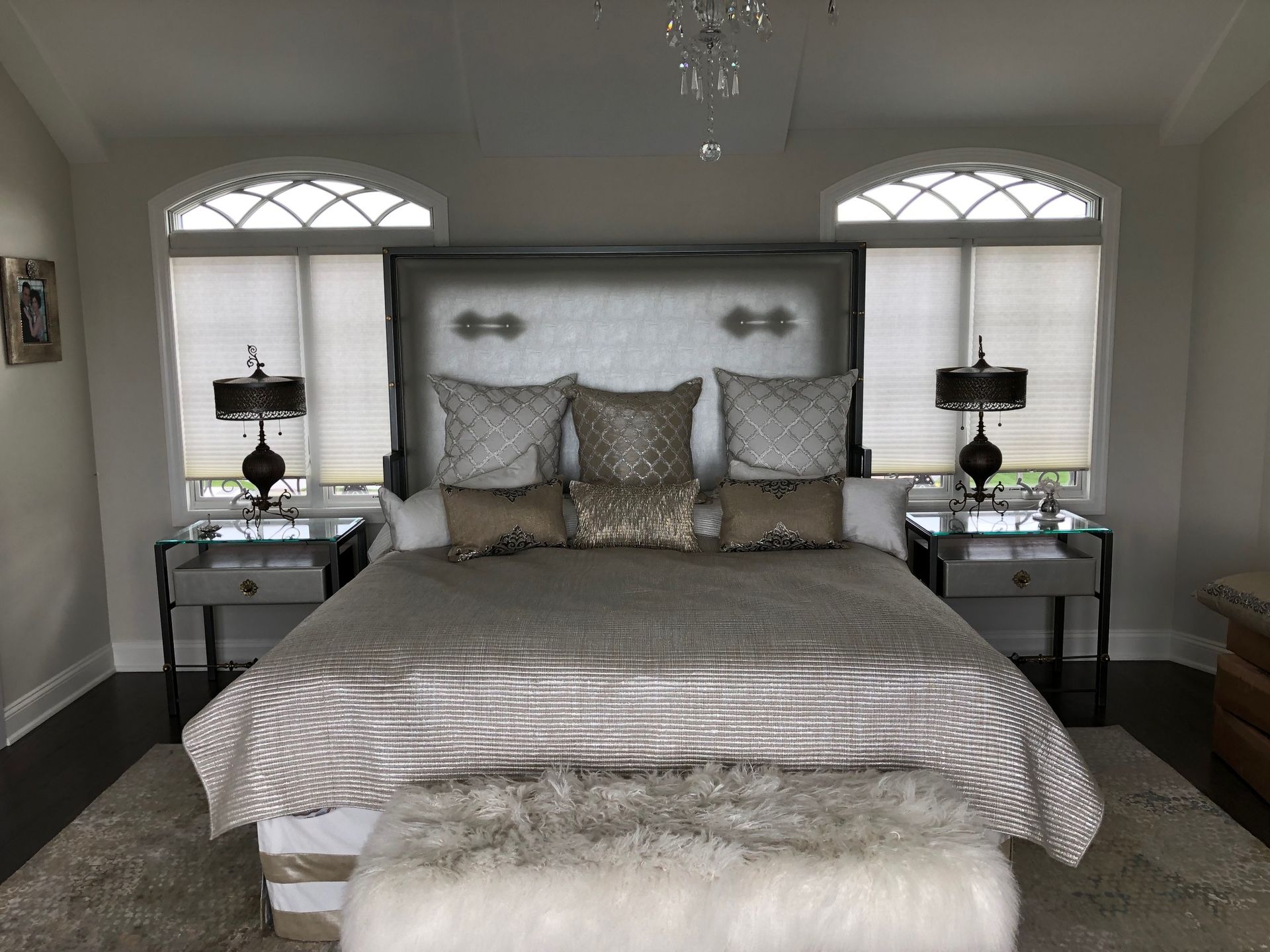 A bedroom with a bed , two nightstands and two windows.