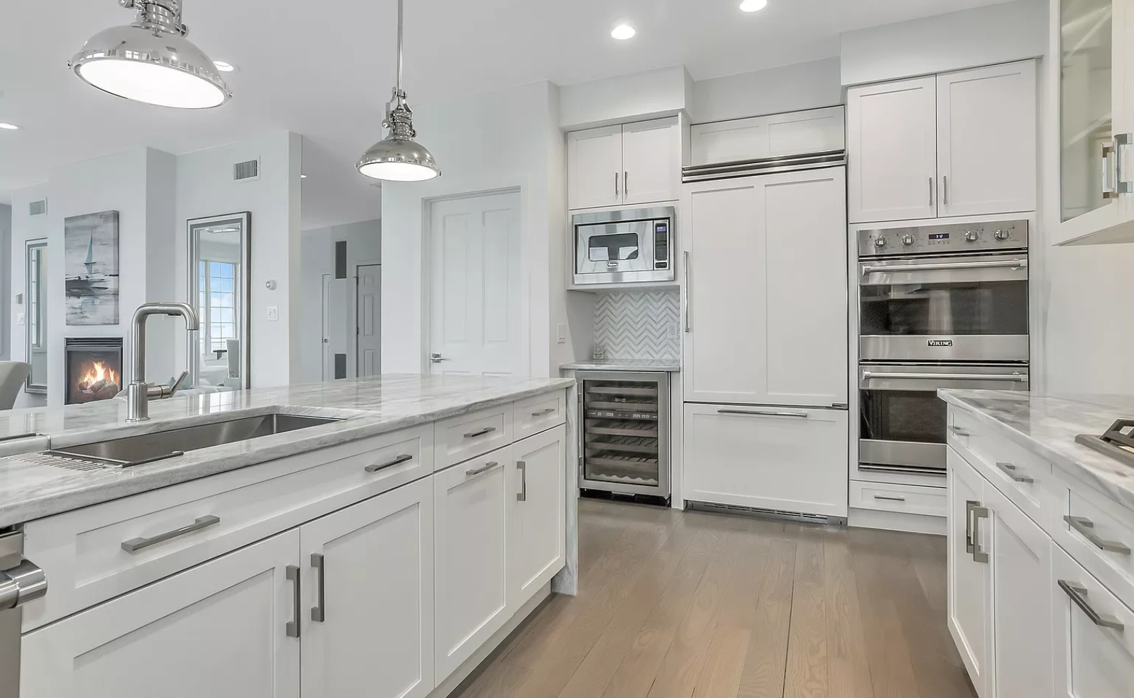 A kitchen with white cabinets , granite counter tops , and stainless steel appliances.